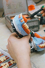 Lab tech building dentures from wax