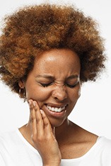 Woman with white shirt and tooth pain that requires an emergency dentist in Park Slope, NY