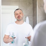 Man rinsing with mouthwash in bathroom